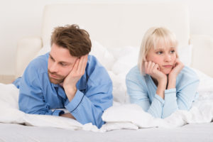 Sad Couple Lying In Bed Ignoring Each Other In Bedroom At Home