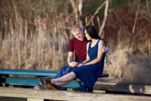 Young interracial couple quietly praying together on wooden pier over water