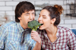 Couple having fun eating broccoli