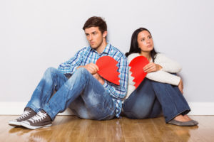 Young couple sitting on floor with broken heart at home