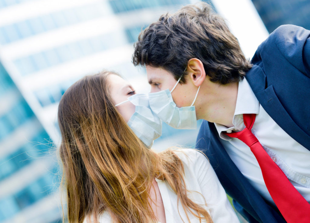 Lovers workers kissing with protective face mask against pollution